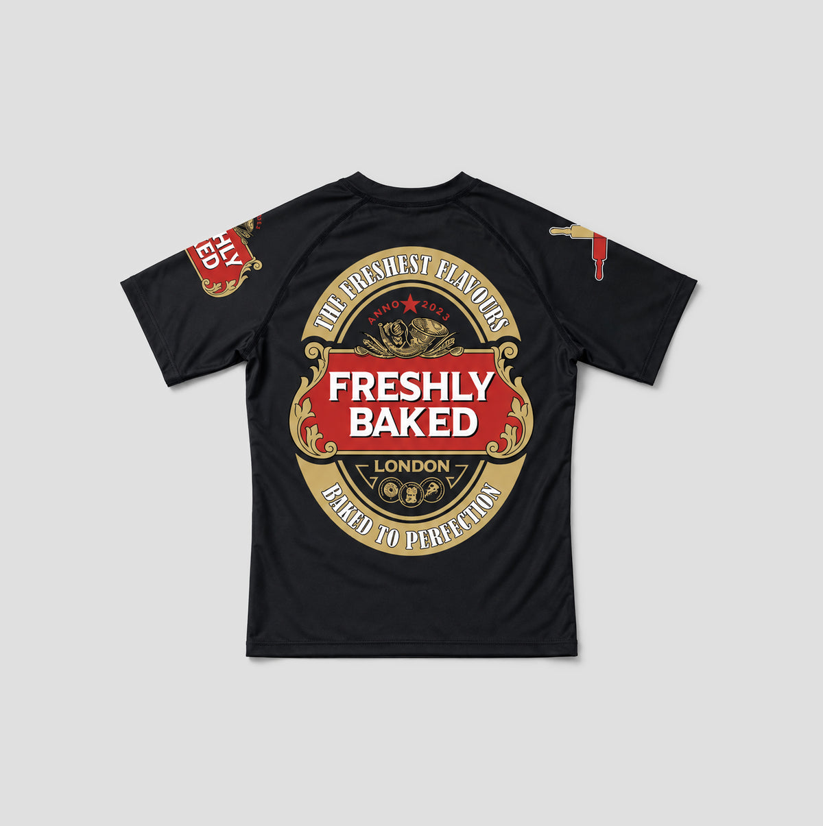 A black short-sleeve t-shirt with a large circular graphic on the back. The graphic features a red and gold design with the text 'FRESHLY BAKED', 'LONDON', and 'THE GREATEST FLAVOURS BAKED TO PERFECTION'.