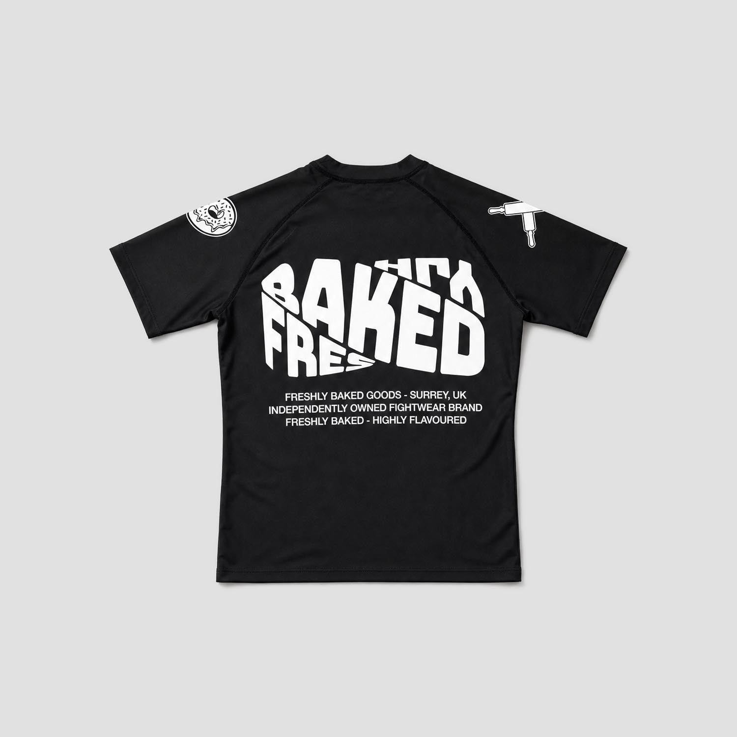 A black short-sleeve raglan t-shirt with bold white text on the front reading 'FRESHLY BAKED', displayed flat against a light gray background.