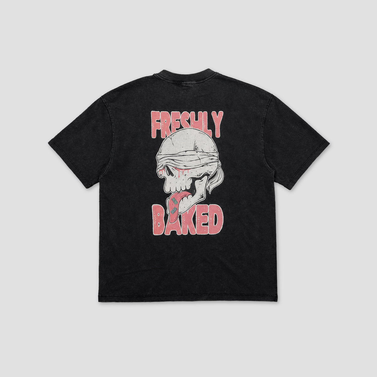 A black short-sleeve t-shirt with a graphic on the back featuring a bandaged skull and the words 'FRESHLY BAKED' in pink, shown against a light gray background.