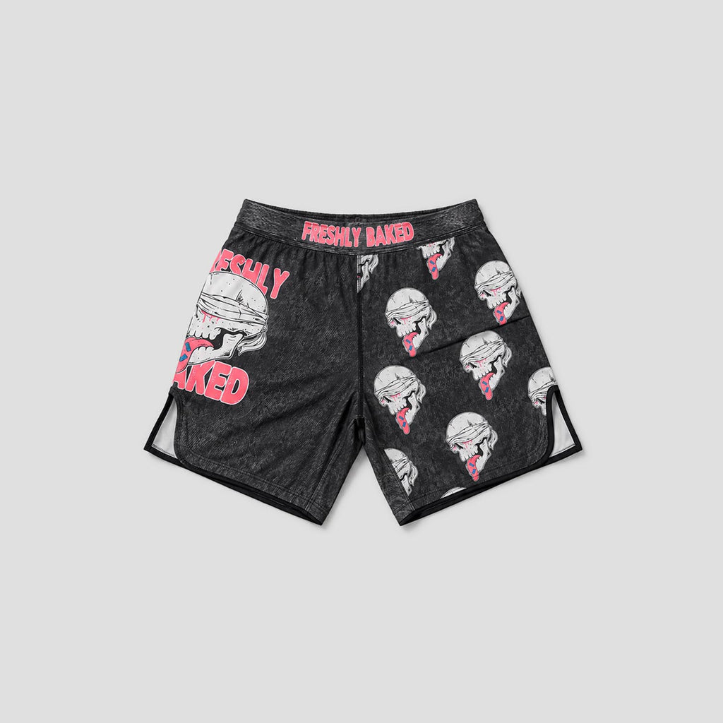 Black athletic shorts with a dark gray heathered texture, featuring a pink and white graphic of a skull wearing a chef's hat on the left leg, an all-over print of the same chef skull on the right leg, and pink 'FRESHLY BAKED' text on the waistband and left leg.