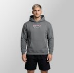 A man wearing a gray pullover hoodie with a 'Freshly Baked' graphic on the chest, paired with black athletic shorts, standing against a light gray studio background.