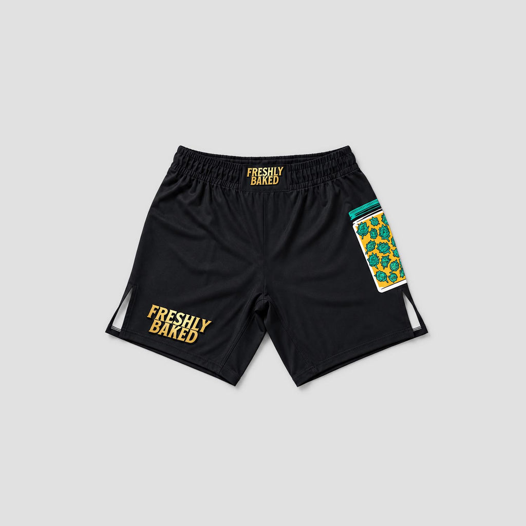 Black athletic shorts with 'FRESHLY BAKED' printed in yellow on the left leg and waistband, featuring a colorful patterned pocket on the right leg, shown on a light gray background.