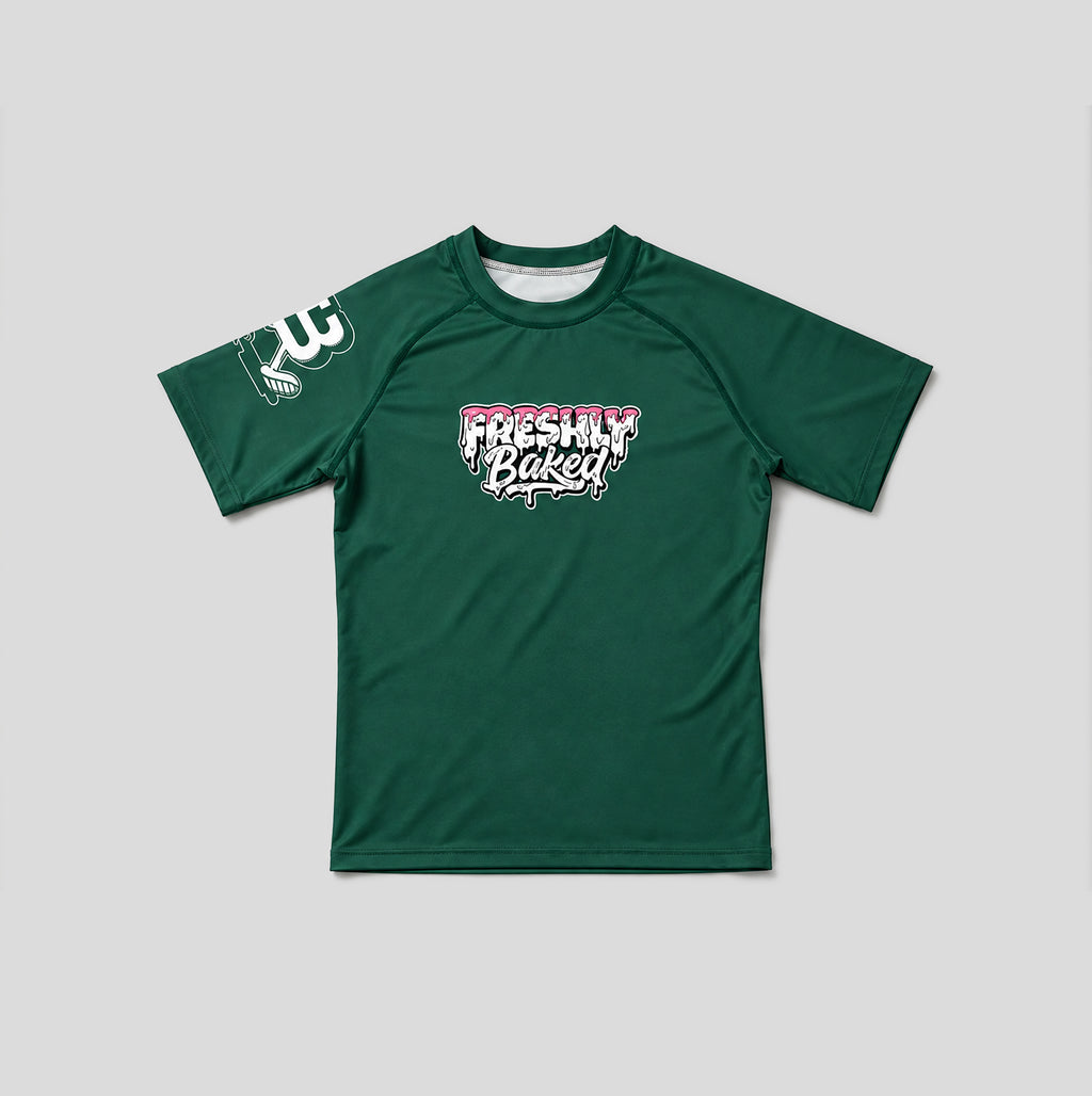 A dark green short-sleeve athletic t-shirt with a 'Freshly Baked' graphic on the chest and a white graphic on the right sleeve, displayed flat against a light gray background.