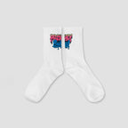 A pair of white crew socks with a colorful graffiti-style graphic near the cuff, displayed against a solid light gray background.