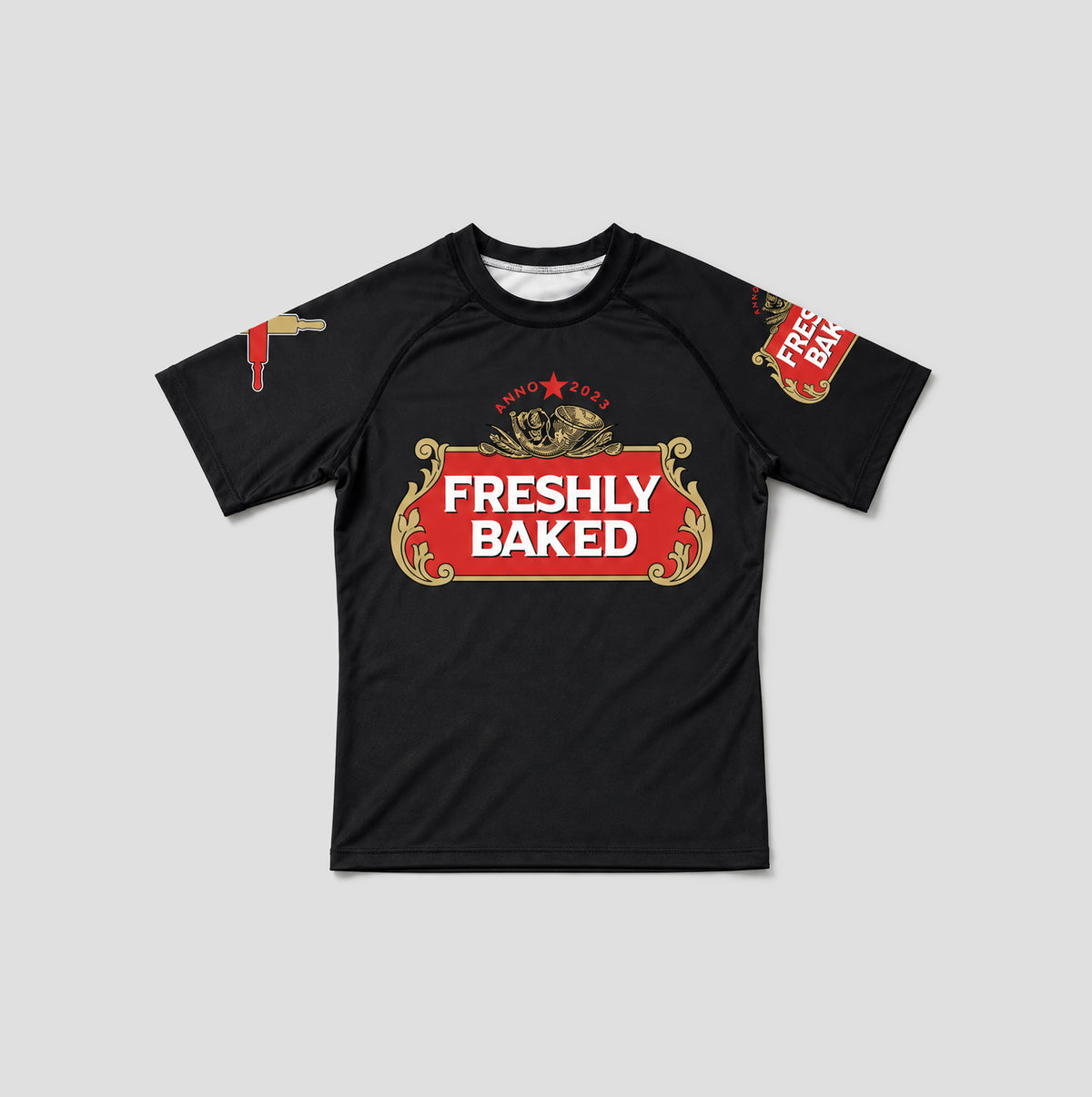 A black short-sleeve athletic t-shirt with a red and gold 'Freshly Baked' graphic on the chest, featuring a bee illustration and 'FRESHLY BAKED' text on the sleeves, shown on a light gray background.