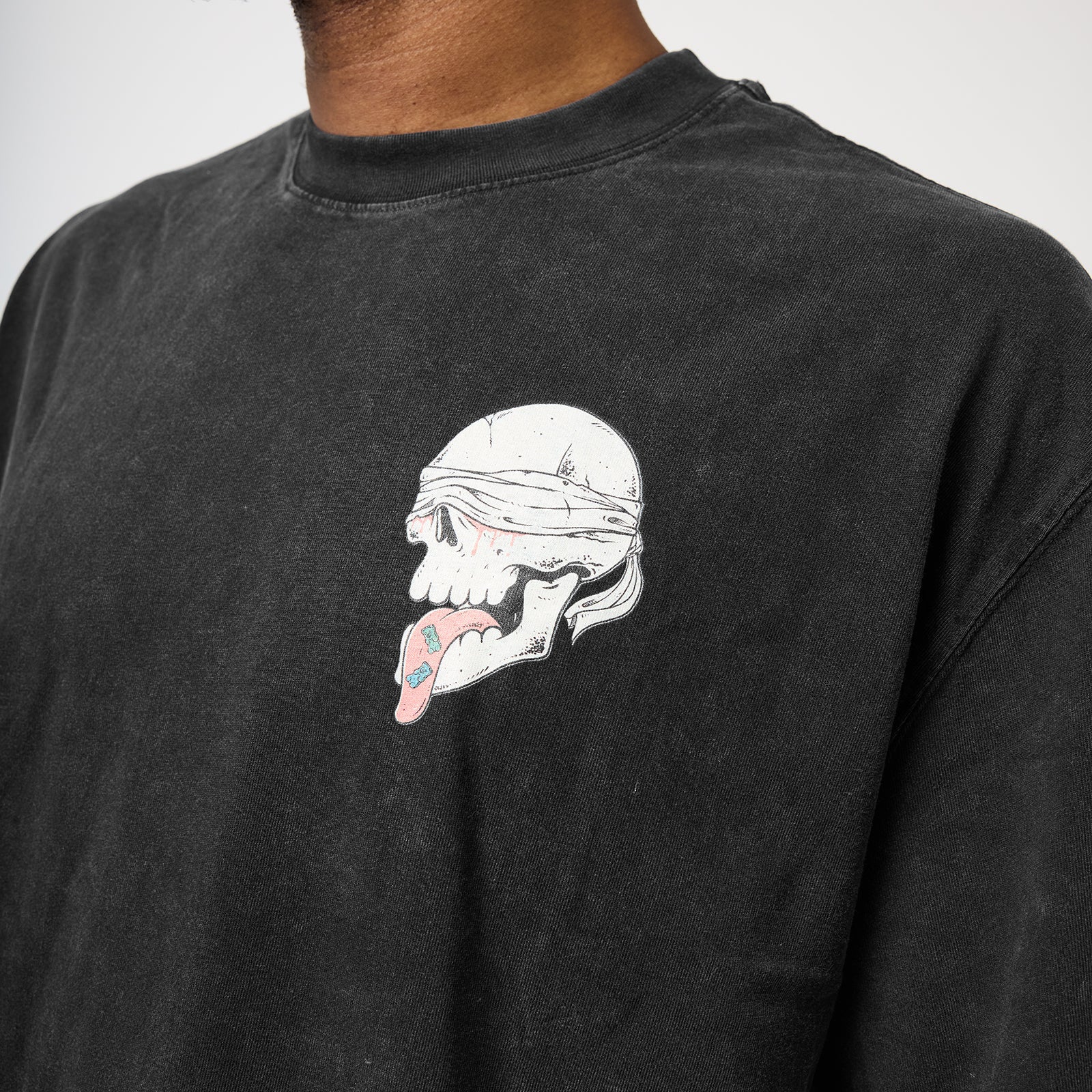 Close-up of a person wearing a faded black long-sleeve t-shirt with a graphic of a blindfolded skull on the chest.