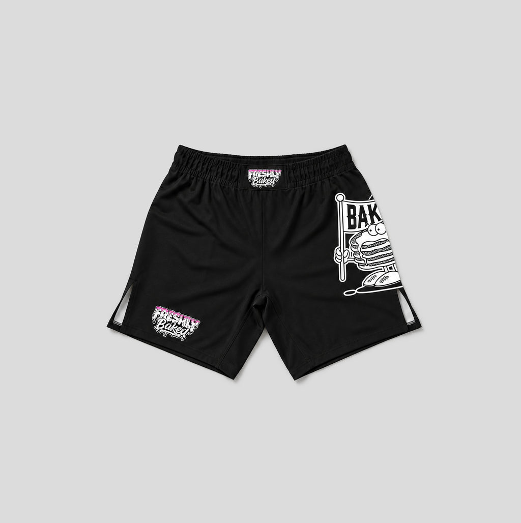 Black athletic shorts with white and pink graphics, featuring a large cartoon graphic on the right leg and a smaller graphic on the left leg, shown against a solid gray background.