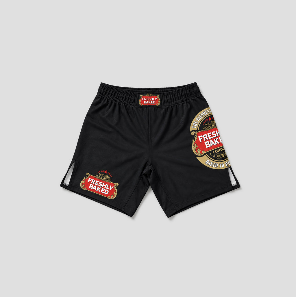 Black athletic shorts featuring 'Freshly Baked' brand graphics, including a large circular logo on the left leg and a smaller rectangular patch on the right leg, displayed against a light gray background.