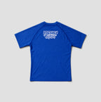 A royal blue short-sleeve rash guard with raglan sleeves and a white 'Freshly Baked' logo printed on the upper back, shown against a neutral light gray background.