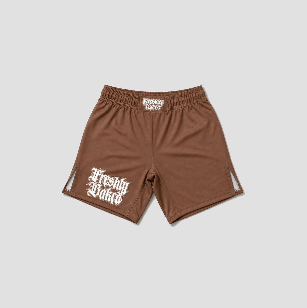 A pair of brown athletic shorts with a white 'Freshly Baked' logo printed on the left leg, displayed flat against a light gray background.