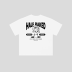 A white short-sleeve t-shirt with a black graphic print on the front. The graphic features the text 'HALF BAKED' in a bold, arched font above a hand holding a donut with a strawberry, with 'ALWAYS FRESH' and 'STAY FRESH, STAY BAKED' written below.