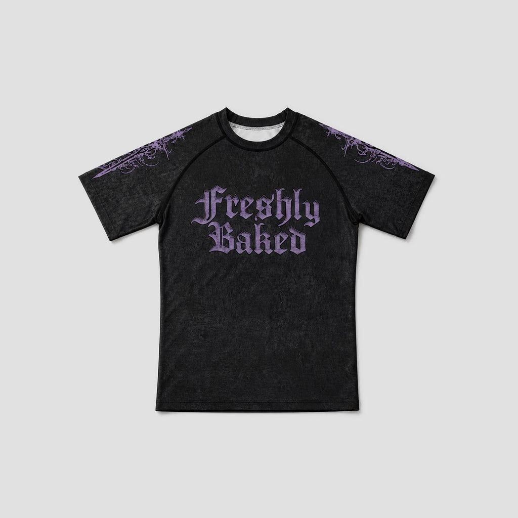 A black short-sleeve raglan t-shirt with 'Freshly Baked' printed in a purple gothic font on the chest, featuring purple gothic patterns on the shoulders, shown against a light gray background.
