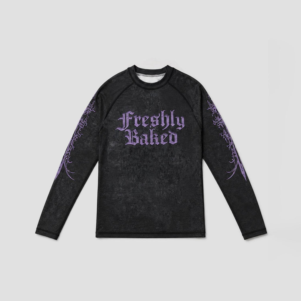 A long-sleeve black athletic shirt with a purple 'Freshly Baked' gothic text graphic on the chest and purple tribal-style sleeve prints, displayed flat against a light gray background.