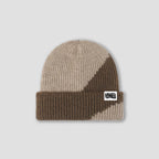 A ribbed knit beanie hat in beige and brown with a small white square patch on the cuff that reads 'FRESHLY BAKED'. The hat is photographed flat against a light gray background.