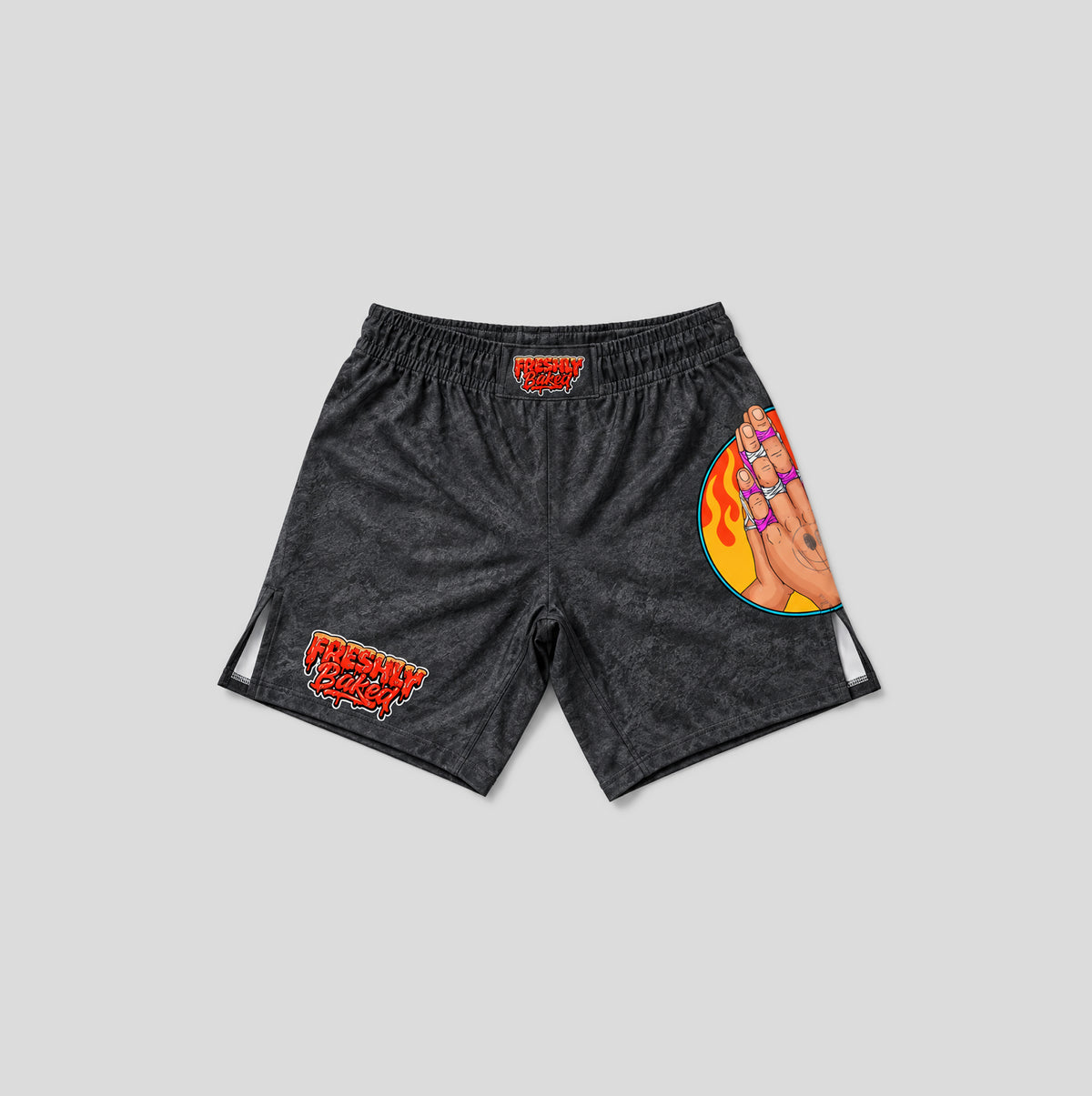 Black acid-wash athletic shorts with red and orange graphics, including 'FRESHLY BAKED' text and a hand illustration with flames, shown on a light gray background.