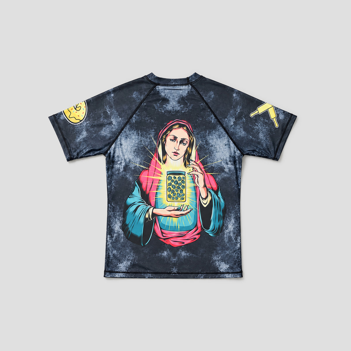 A short-sleeve athletic rash guard with a dark blue and black mottled tie-dye pattern, featuring a large graphic print of a religious figure holding a glowing holy card on the front. The sleeves have yellow graphic accents, and the shirt is displayed flat against a neutral light gray background.