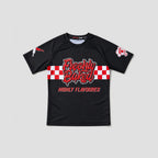 A black short-sleeve athletic t-shirt with a red and white checkered graphic across the chest reading 'Freshly Baked' and 'HIGHLY FLAVOURED' in red. The shirt features a small red and white logo on the right sleeve and a small white graphic on the left sleeve, displayed against a solid light gray background.