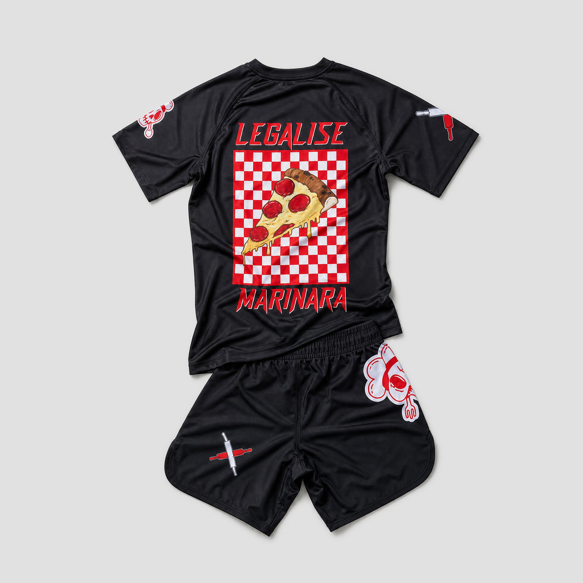 A two-piece black swimwear set consisting of a short-sleeve rash guard and matching shorts, laid flat on a light gray background. The back of the rash guard features a large graphic of a pepperoni pizza slice on a red and white checkered square, with the words 'LEGALISE' above and 'MARINARA' below in red.