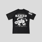 A black short-sleeve t-shirt with a white graphic print on the front and sleeve, featuring the text 'FRESHLY BAKED' and a cartoon character with a basket of cookies.