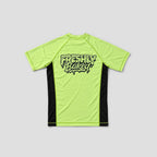 A short-sleeve athletic jersey shown from the back, featuring a bright neon yellow-green body with black side panels and a black graphic text print reading 'Freshly Baked' across the upper back, set against a solid light gray background.