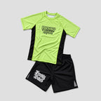A unisex athletic set consisting of a short-sleeve performance shirt and matching shorts, laid flat on a light gray background. The shirt is bright neon yellow-green with black side panels and a black graphic on the chest reading 'Freshly Baked'.