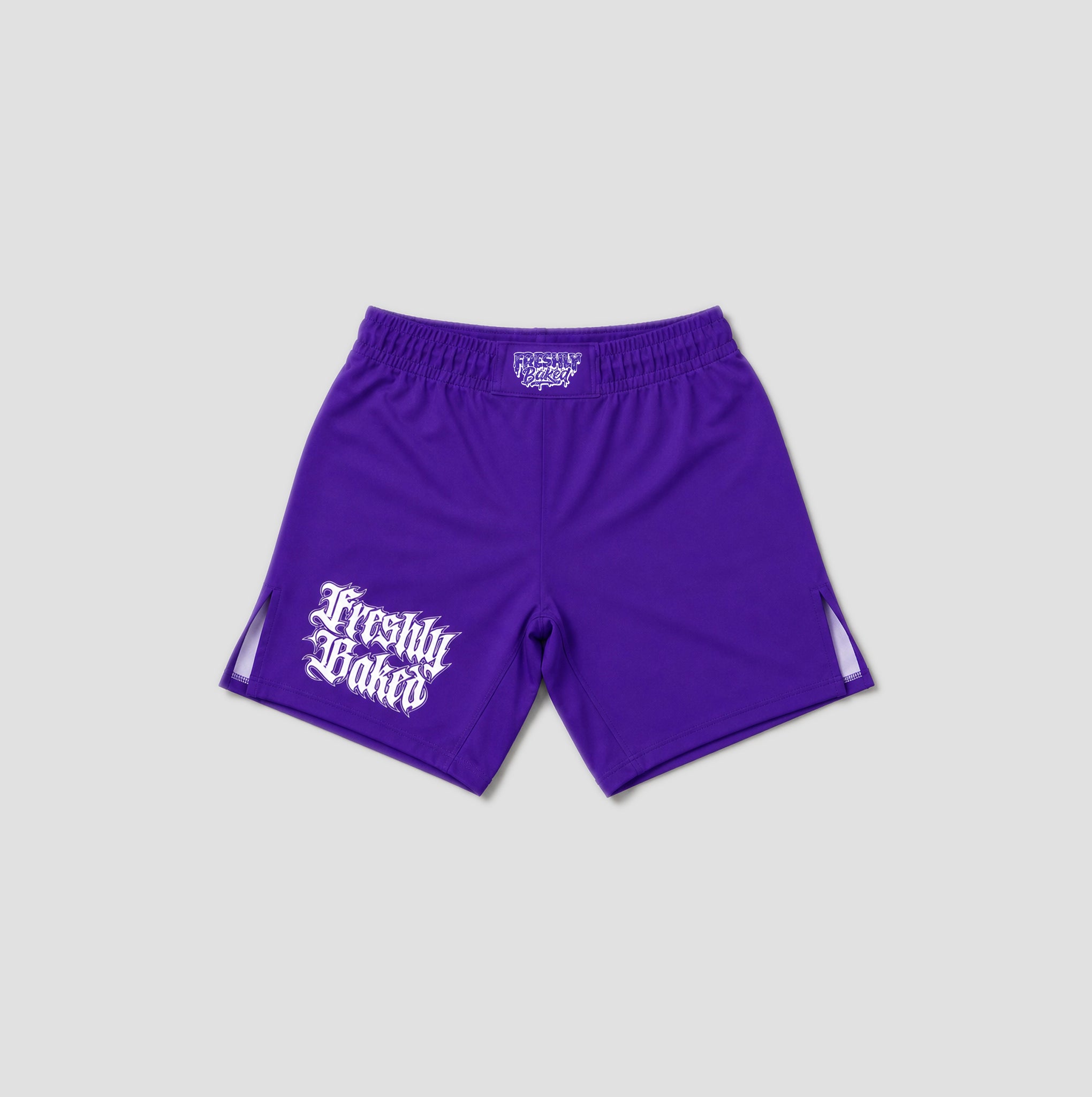 Purple athletic shorts with a white 'Freshly Baked' logo printed on the left leg, displayed against a light gray background.