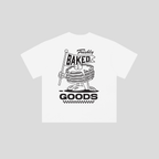 A white short-sleeve t-shirt with a black graphic print of a cartoon stack of pancakes holding a 'Freshly Baked Goods' sign, displayed on a solid light gray background.