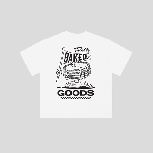 A white short-sleeve t-shirt with a black graphic print of a cartoon stack of pancakes holding a 'Freshly Baked Goods' sign, displayed on a solid light gray background.