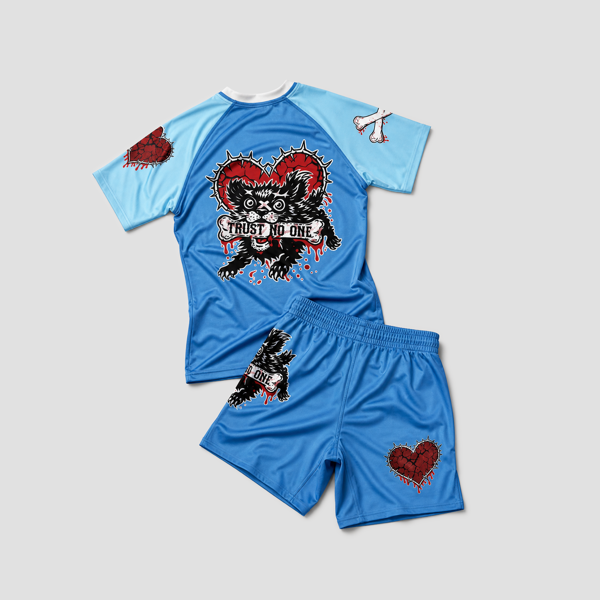 A two-piece athletic rash guard and shorts set in light blue, featuring a large black and red skull-and-heart graphic on the shirt with the words 'TRUST NO ONE', matching blue shorts with a small heart graphic, and white cross details on the sleeves.
