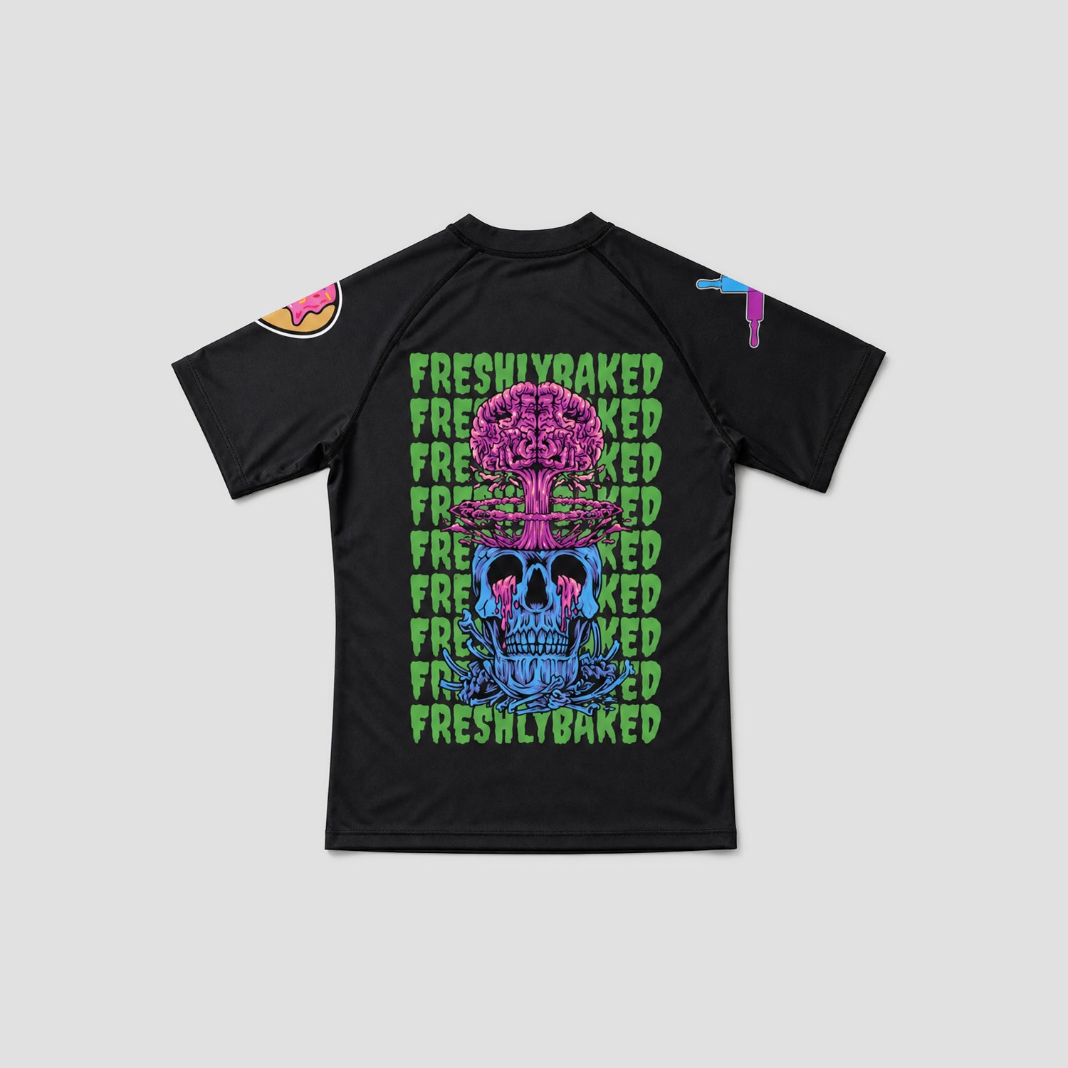 A black short-sleeve t-shirt with a colorful graphic print featuring a skull and tree design, with the word 'FRESHLYBAKED' repeated in green on the front, shown on a light gray background.