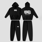 A black two-piece tracksuit set shown from both front and back views, including a cropped hoodie with white graphic text and matching jogger pants, displayed on a light gray background.
