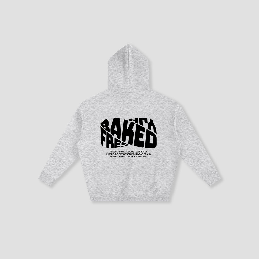 A light heather gray hoodie shown from the back, featuring a bold black graphic print that reads 'FRESHLY BAKED' with smaller text underneath, displayed on a neutral light gray background.