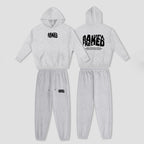 A two-piece kids' tracksuit shown from both front and back views. The set consists of a light heather gray hooded sweatshirt and matching jogger pants.