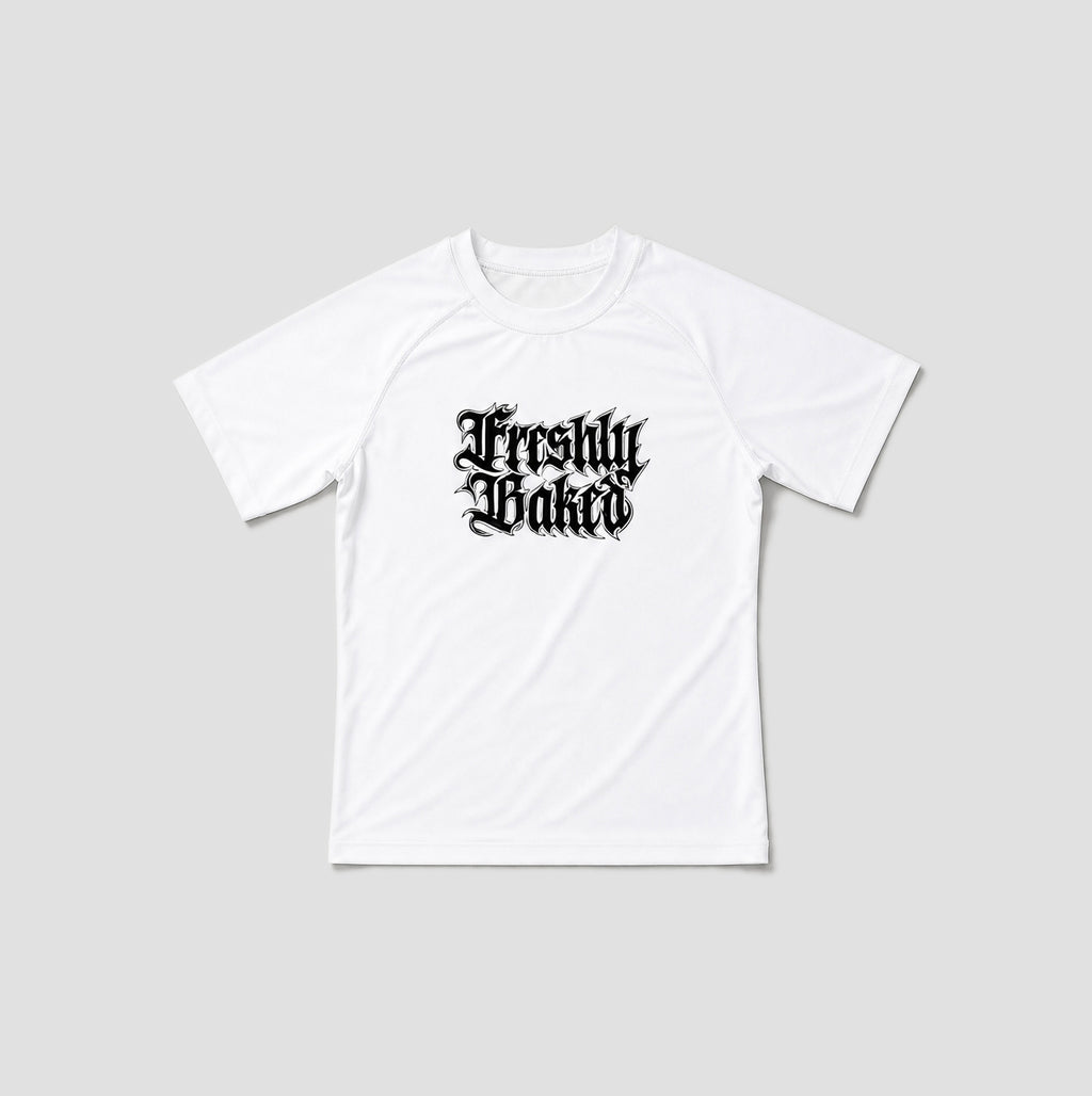 A white short-sleeve t-shirt with a black gothic-style 'Freshly Baked' graphic printed on the chest, displayed against a solid light gray background.