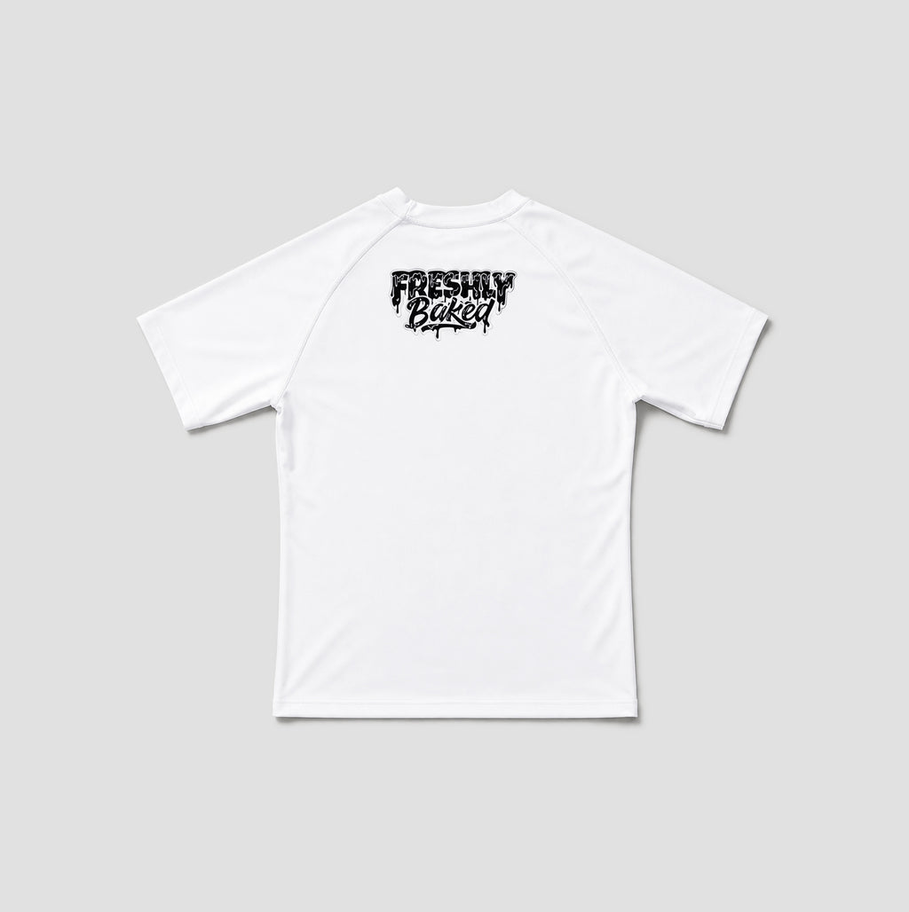 A white short-sleeve t-shirt shown from the back, featuring a black distressed graphic print that reads 'FRESHLY BAKED' across the upper back, set against a solid light gray background.