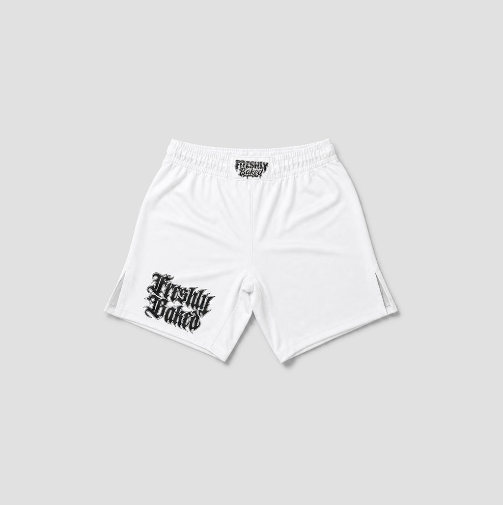 White athletic shorts with a black gothic 'Freshly Baked' logo printed on the left leg, displayed on a light gray background.