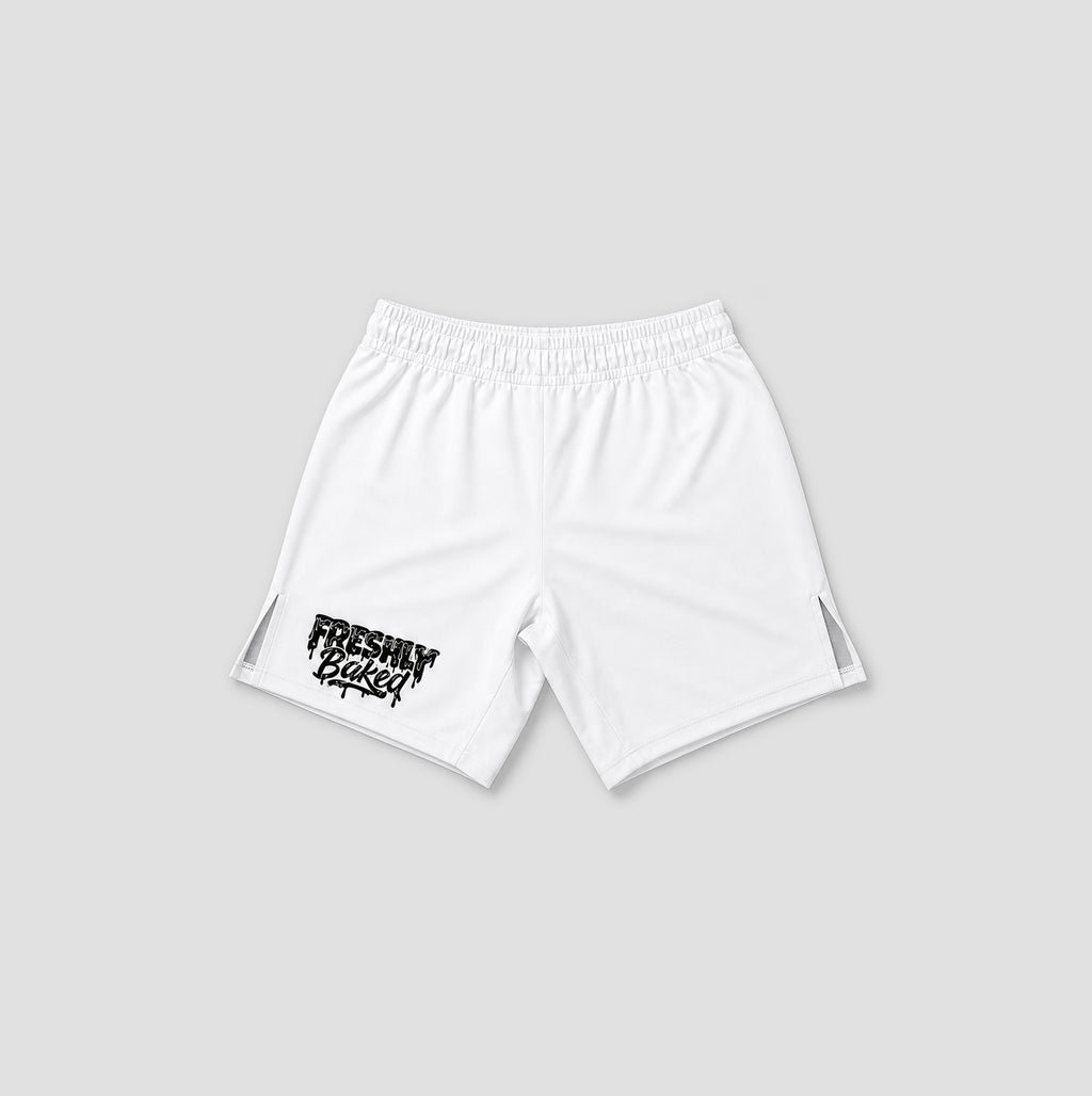 White athletic shorts with an elastic waistband, featuring a black distressed 'FRESHLY BAKED' graphic on the lower left leg and side cutout details, shown against a light gray background.