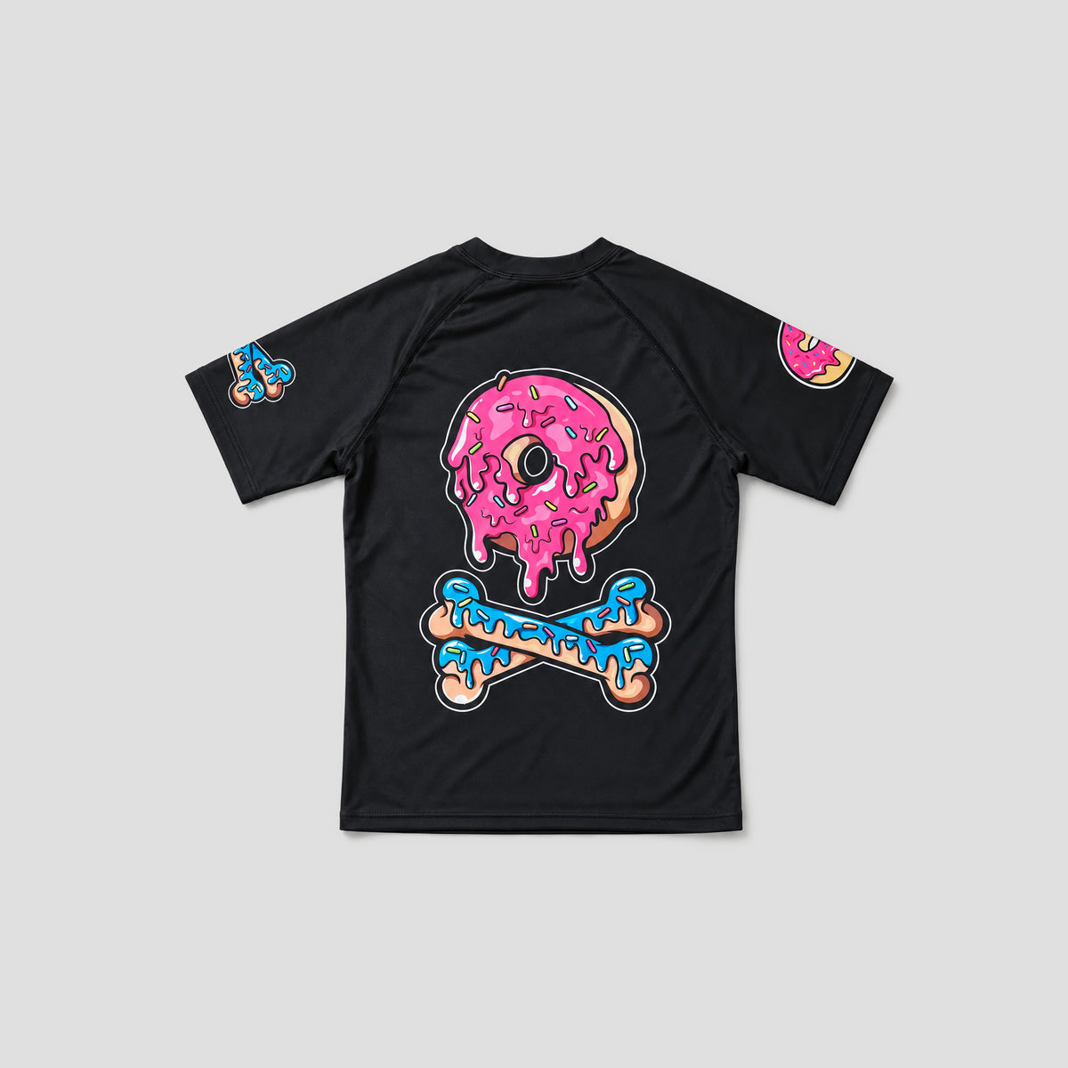 A black short-sleeve t-shirt with a large graphic on the back featuring a pink frosted donut and a blue bone. Smaller versions of the graphic appear on both sleeves, set against a solid light gray background.