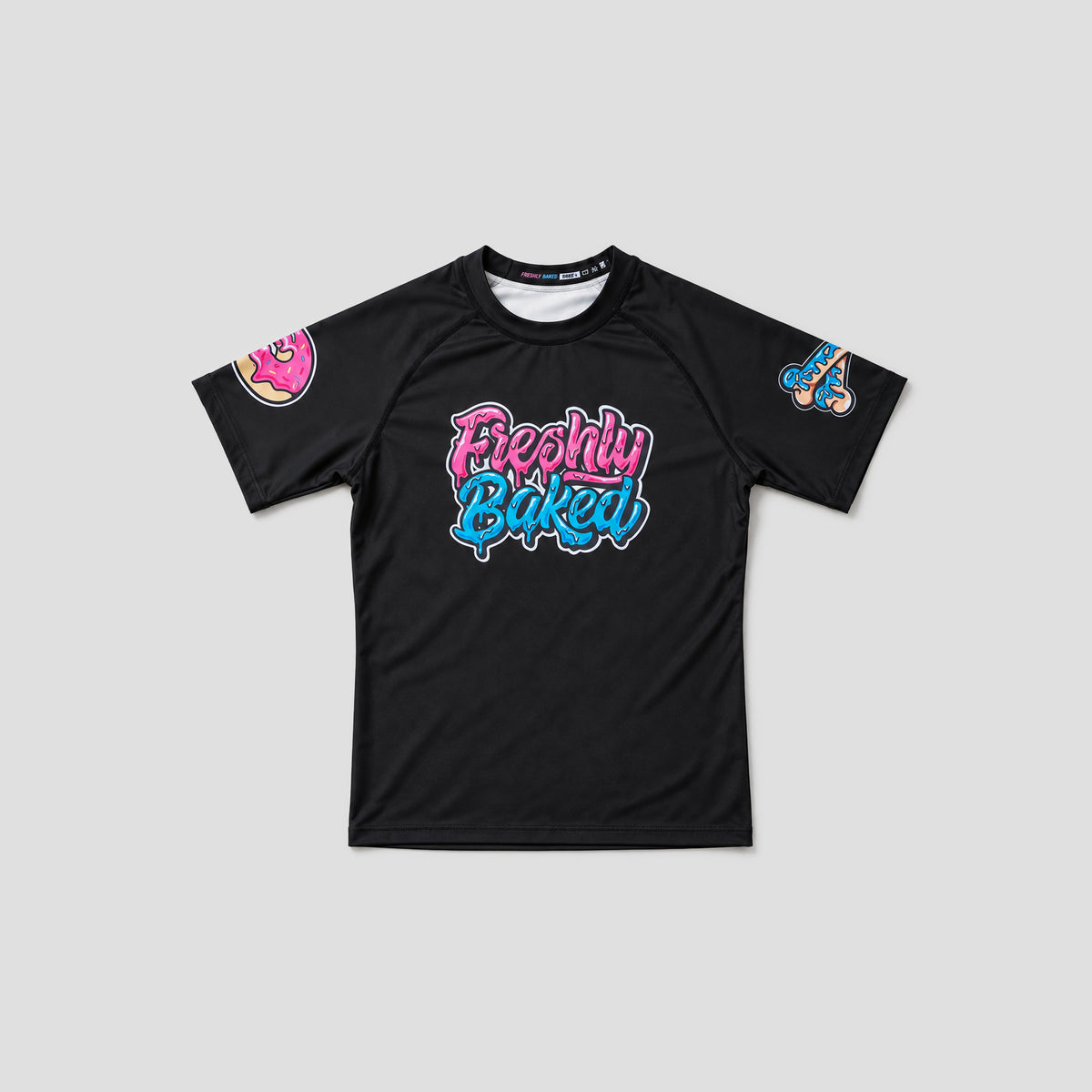 A black short-sleeve t-shirt with a colorful graphic on the chest reading 'Freshly Baked' in pink and blue bubble letters, with additional graphics on both sleeves, shown against a light gray background.