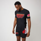A man modeling a black short-sleeve t-shirt and matching shorts set with colorful graphic prints, including 'Freshly Baked' on the chest and a pink donut on the sleeve.