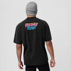 A man wearing a black washed t-shirt from the back, featuring a colorful 'Freshly Baked' graphic in pink, yellow, and blue on the upper back. He is also wearing a gray beanie, photographed against a solid light gray background.