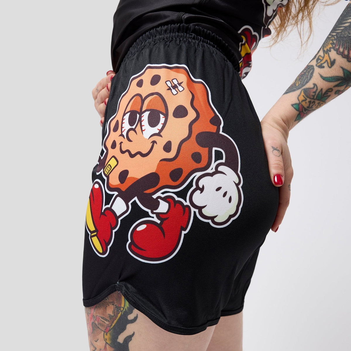 Black athletic shorts with a large cartoon cookie boxing graphic, shown on a model with tattooed arms against a light gray background.