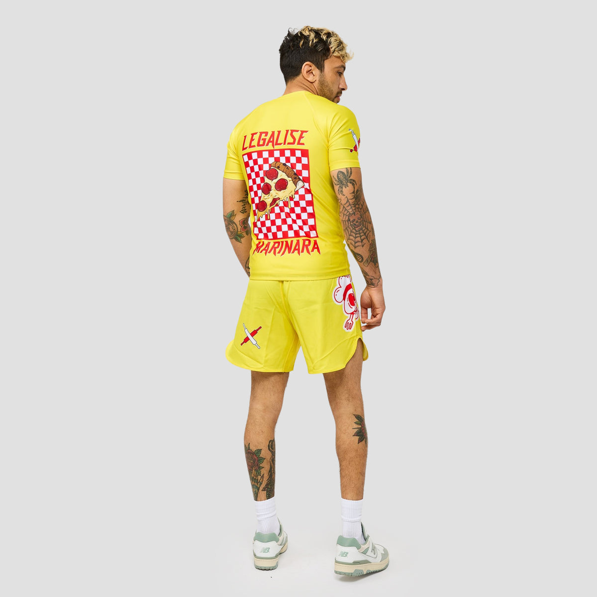 A man shown from the back wearing a bright yellow soccer kit with red and white graphic prints, including the word 'LEGALISE' and 'SAPNARA' on the back, against a light gray studio background.